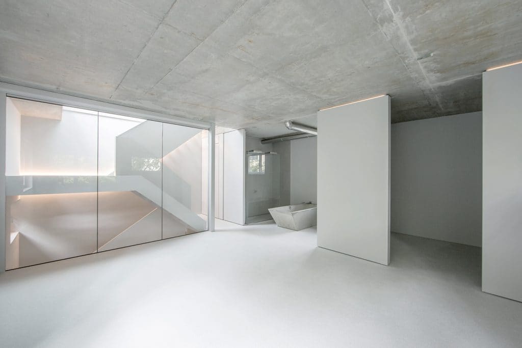 White living space with an exposed concrete ceiling and a glass wall