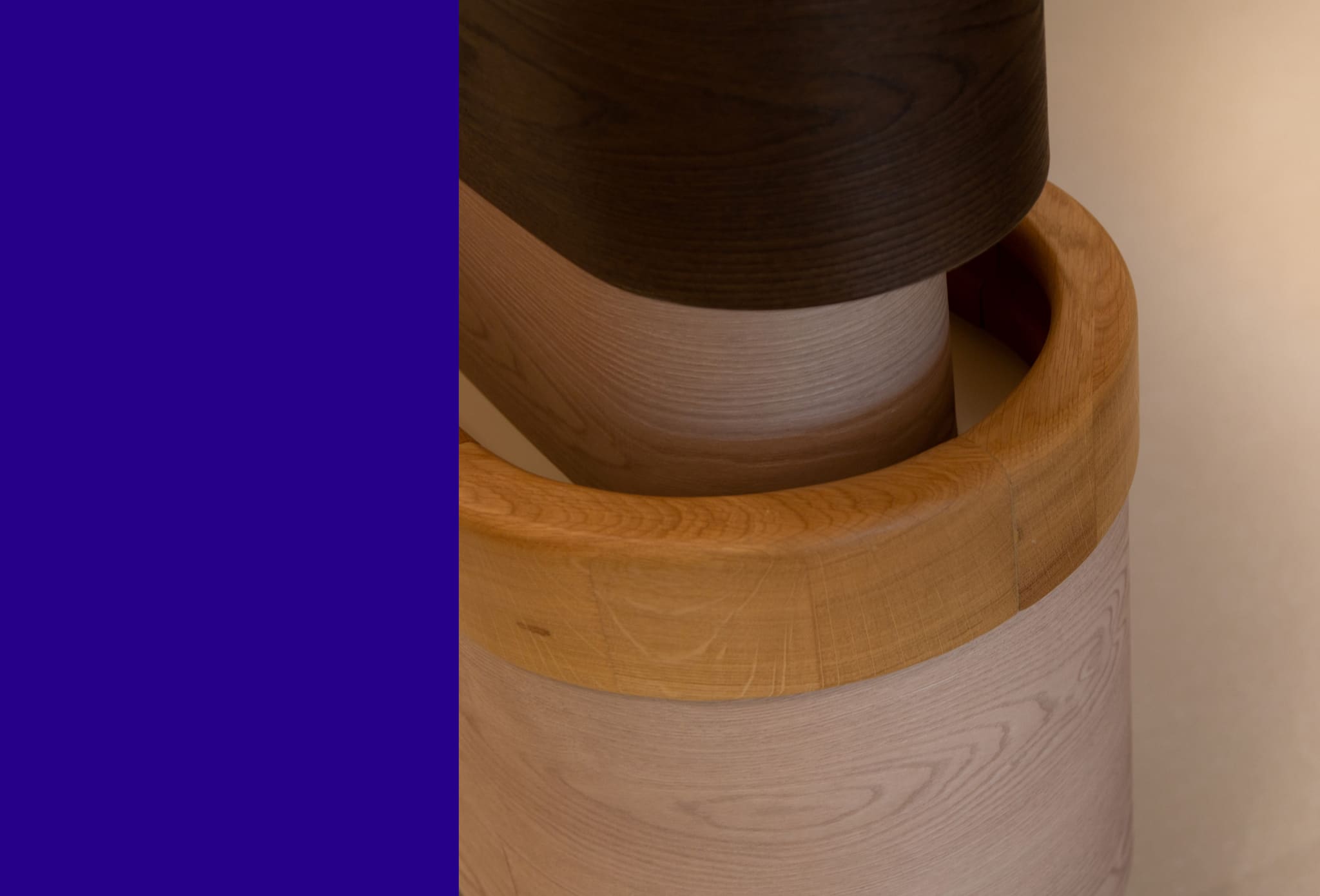 Close-up of a rounded oak handrail running around a curved wall of light and dark timber bands