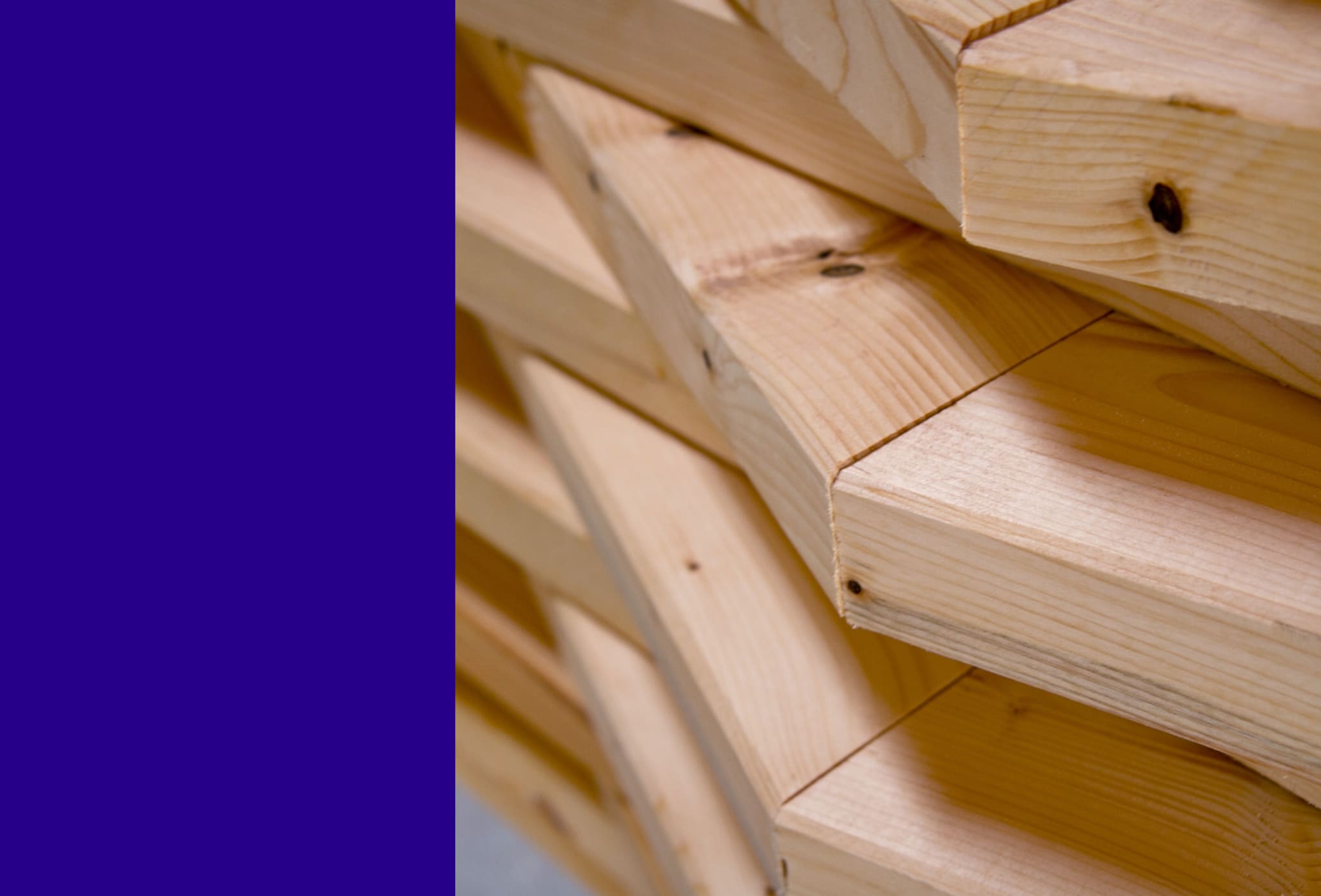 Close-up of offset, angle-cut timber boards with visible grain, violet colour field on the left
