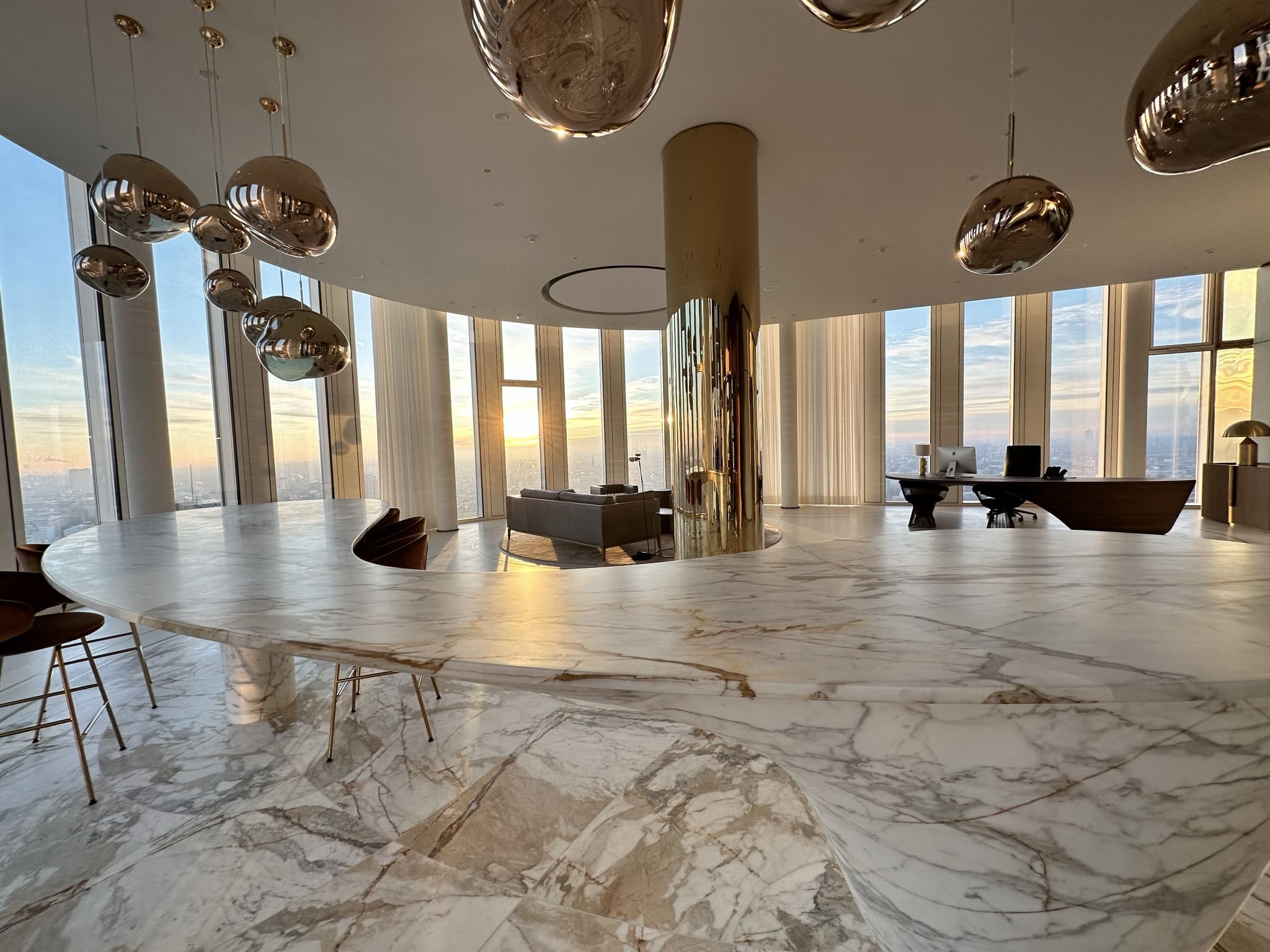 Lobby des Penthouses mit Marmortresen, Kugelleuchten und Messingsäule im Abendlicht