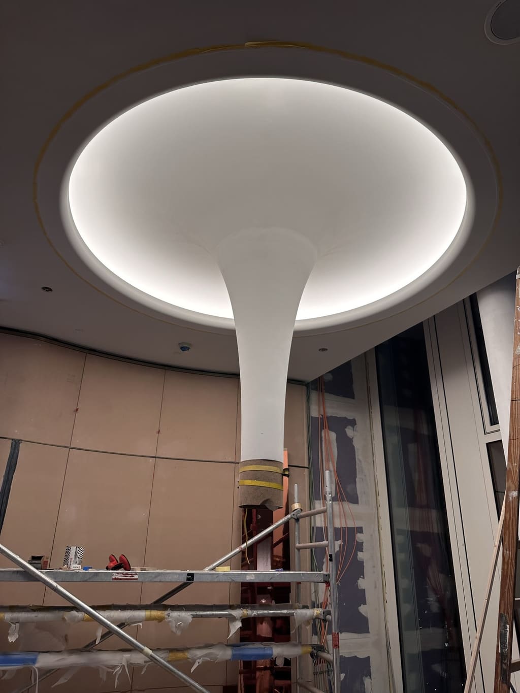 Elliptische Deckenkuppel mit Lichtvoute über einer Stütze, davor das Gerüst im Bau
