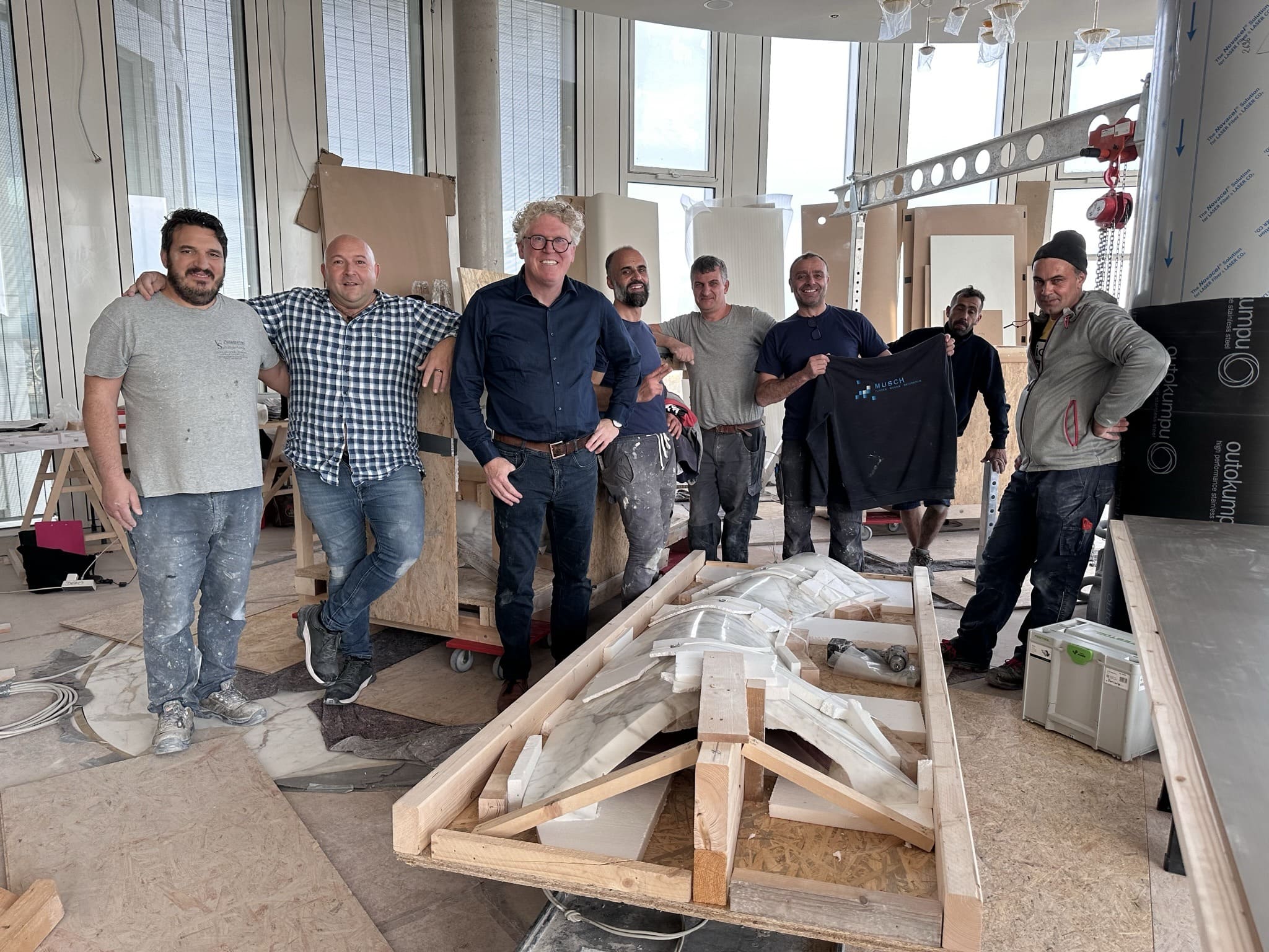 Das Team von Musch neben dem auf Holzböcken liegenden Marmortresen auf der Baustelle