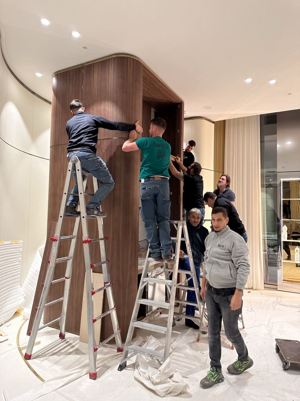 Tischler auf Leitern beim Einbau eines geschwungenen Einbaus aus Nussbaum