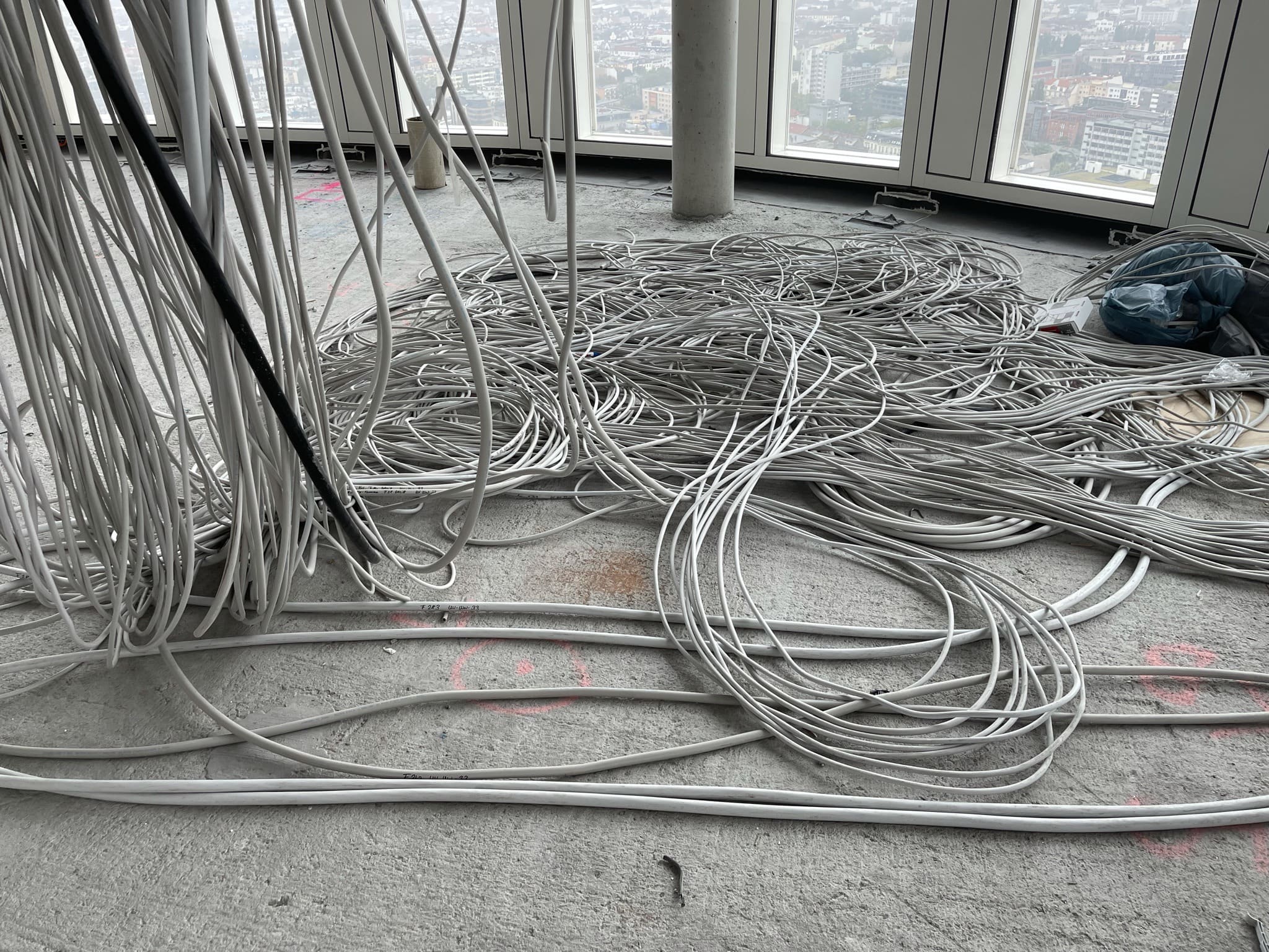 Hunderte Einzelzuleitungen liegen aufgerollt auf dem Rohboden vor der Fensterfront