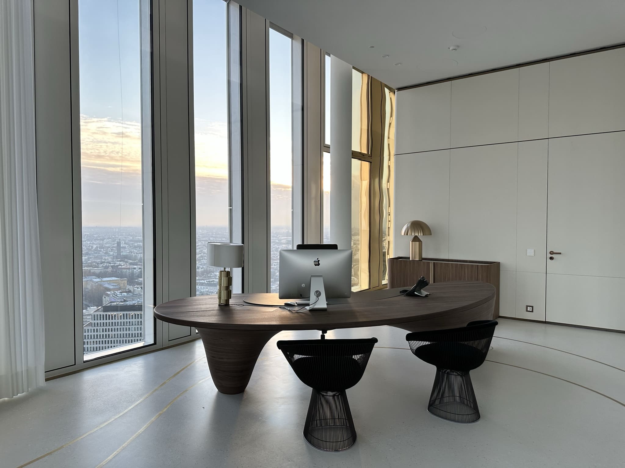 Another workspace with a wooden desk in front of full-height windows, looking out over Berlin.