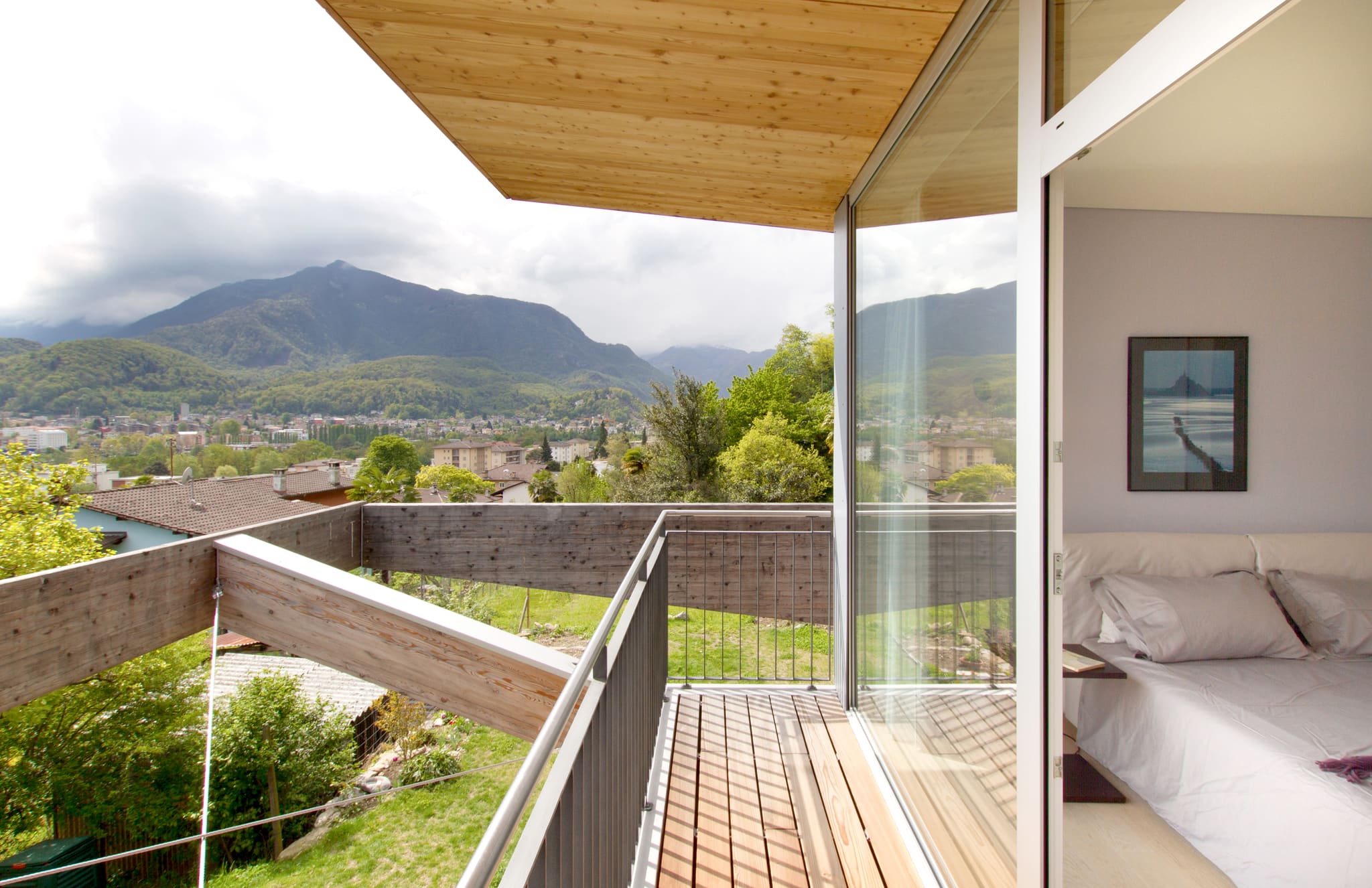 Balkon der Casa Locarno mit Holzdeck und Glasschiebetür zum Schlafzimmer, Blick über Locarno auf die Tessiner Berge