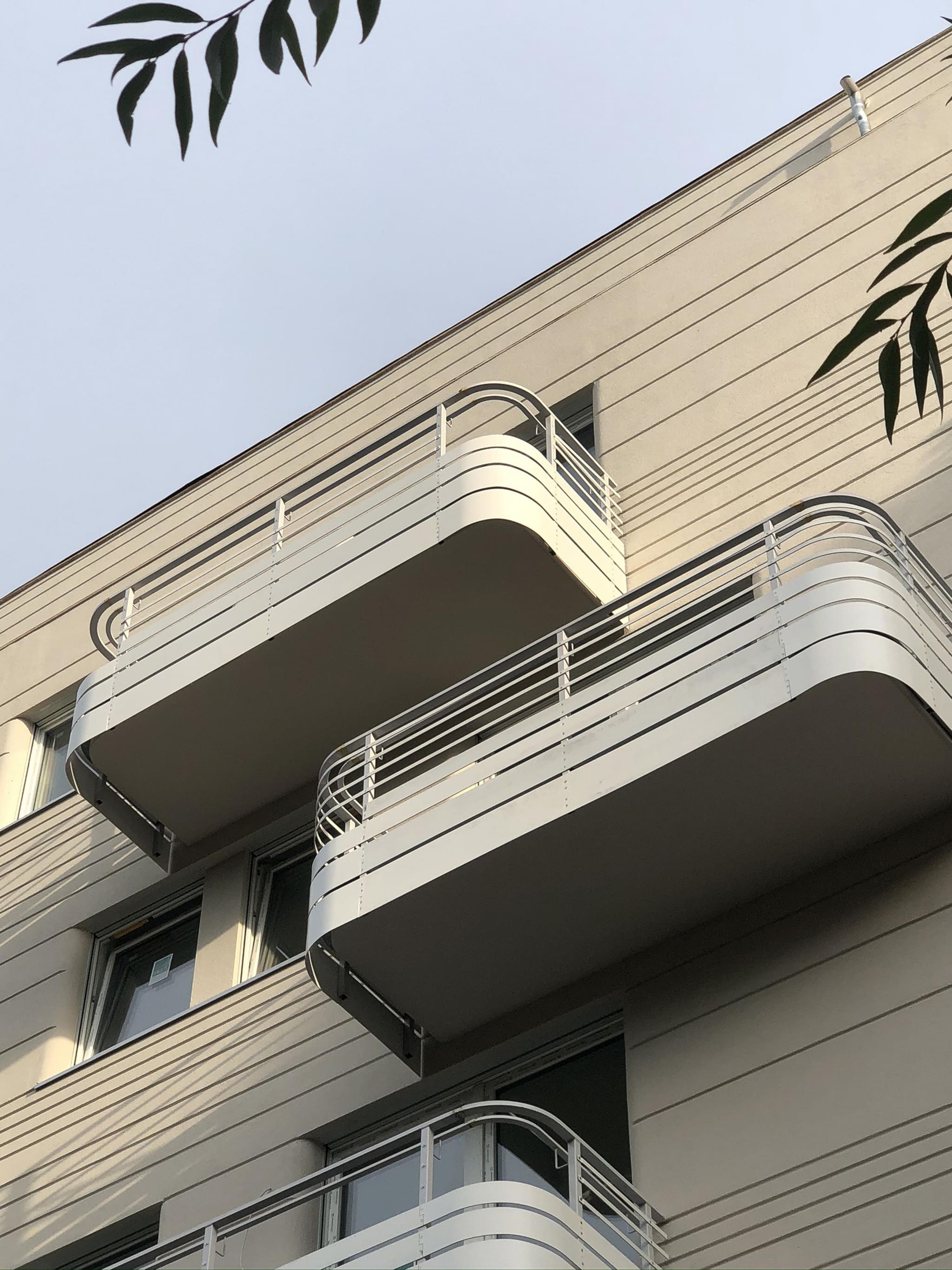Blick von unten auf die helle Fassade des Wohnhauses Nazarethkirchstraße mit gerundeten Balkonen und weißen Stahlgeländern